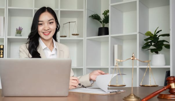 A female Asian lawyer reviews business and real estate laws. Legal consultants provide legal advice and guidance online via laptops in lawyers' offices..