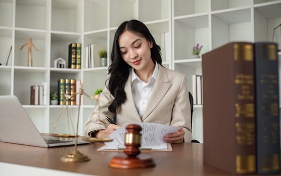 A female Asian lawyer reviews business and real estate laws. Legal consultants provide legal advice and guidance online via laptops in lawyers' offices..