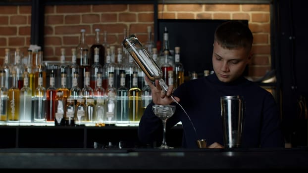 Cool professional caucasian bartender making a cocktail. Media. Authentic barman making alcohol beverages in modern bar