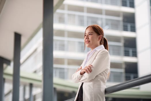 Young happy pretty smiling professional business woman asian, happy confident positive female entrepreneur standing on street arms crossed.