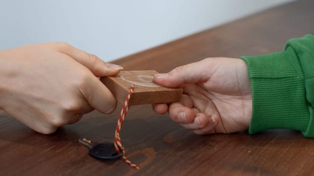 Passing small key with wooden number of a locker. Media. Close up of hands passing and taking a key