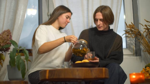 Young man and woman are talking over tea in cafe. Media. Young couple of students are talking with tea in cozy cafe. Couple on student break with tea and comfortable conversation.
