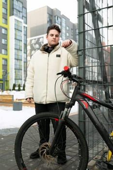 A young European man dressed in a winter jacket rented a bicycle for the weekend.