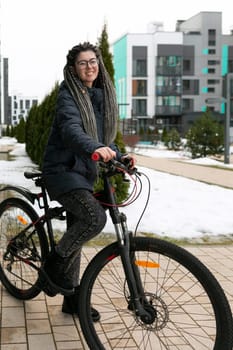 A pretty young woman with a dreadlocked hairstyle rides a rented bicycle.