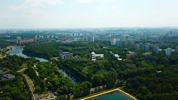 Top view of city with dam and river on sunny summer day. Creative. Beautiful green city with dam and canal on summer day. Skyline of modern city with green parks and clear canal.