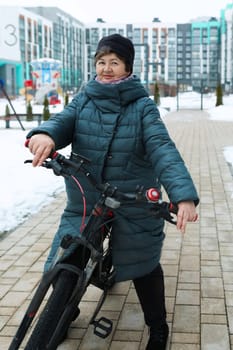 Healthy pensioner woman leads a healthy lifestyle and rides a bike in winter.