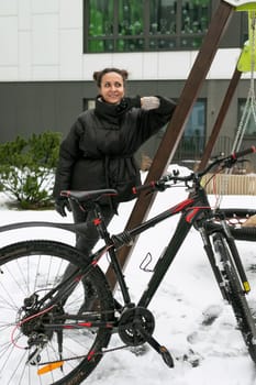 Sports concept, young woman with a bicycle on the background of a high-rise building.