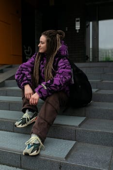 Beautiful young woman with dreadlocks and piercings walks through the city.