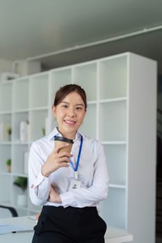 Young successful employee business woman hold craft paper cup coffee stand at desk with laptop pc computer at office. Achievement career concept.