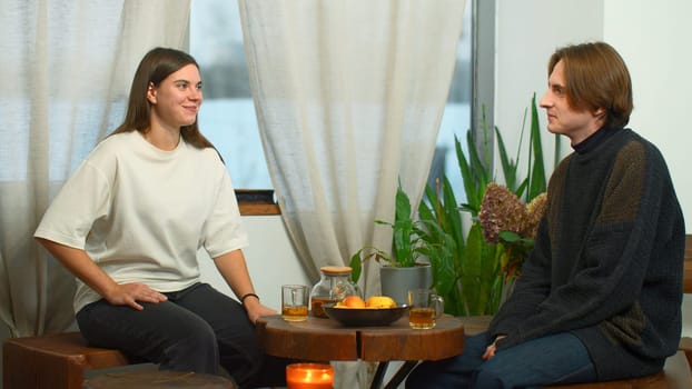 Students communicate and drink tea in cafe. Media. Young man and woman are drinking tea and talking in cafe. Cheerful conversation between young couple of students in cozy cafe.