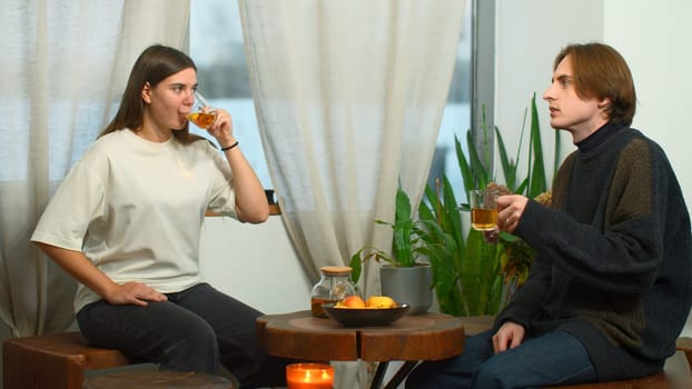 Students communicate and drink tea in cafe. Media. Young man and woman are drinking tea and talking in cafe. Cheerful conversation between young couple of students in cozy cafe.