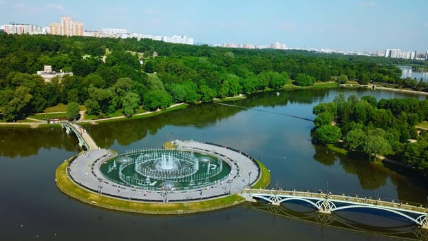 Top view of bridges in city pond with fountains. Creative. Island with bridges and fountains in city pond. Beautiful fountain complex on river island with pedestrian bridges.
