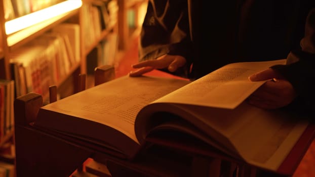 Man reading large mysterious book. Stock footage. Close-up of mysterious man reading ancient forbidden book in library. Secret society with books in night library.
