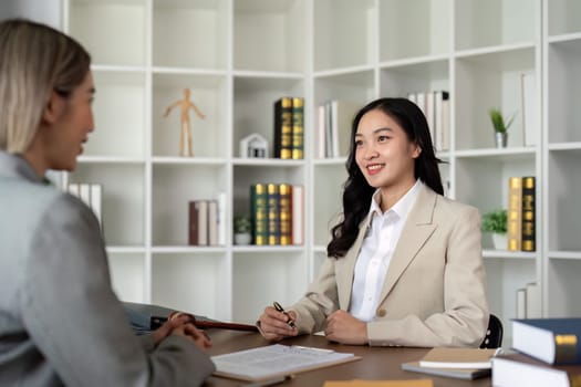 Lawyers woman and businesswoman discussing contract papers sitting at the table. Concepts of law, advice, legal service.