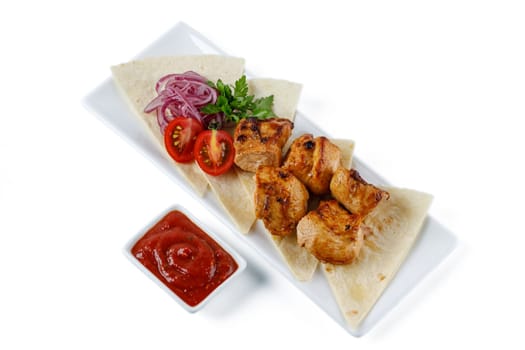 Chicken kebab skewers on a plate over light grey slate, stone or concrete background . Top view with copy space.