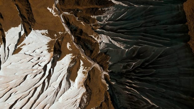 Aerial of wide gorge with rocky cliffs from both sides of small canyon. Clip. Stone slopes and yellow autumn grass