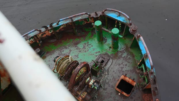 Parts of abandoned fishing boat. Clip. Abandoned boat with rusty parts on cloudy day. Abandoned fishing boat on seashore.