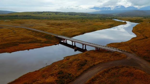 Aerial view of gorgeous nature a bridge between the river shores. Clip. Rural landscape with golden agricultural fields around and the sea shore