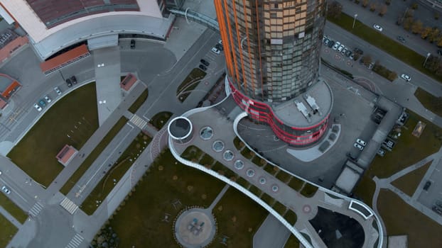 Top view of colorful glowing high-rise on summer day. Stock footage. Beautiful facade of luminous high-rise in modern city. Modern architecture of high-rise buildings with luminous facade.