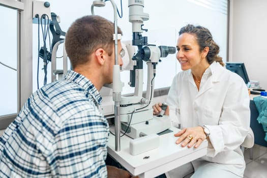 Friendly female ophthalmologist examining a man's eyes with a slit lamp in the clinic