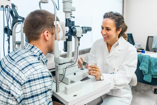 Female optometrist talking with a patient while checking his eyesight in a clinic