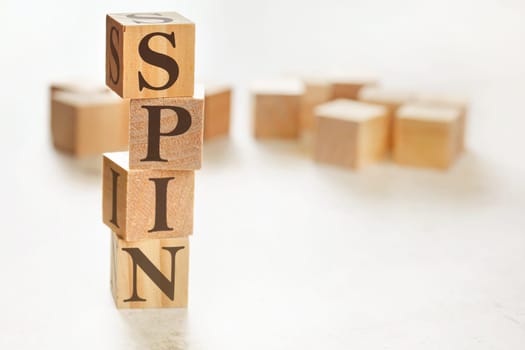 Four wooden cubes arranged in stack with word SPIN (meaning Solution Problem Implication Need) on them, space for text / image at down right corner