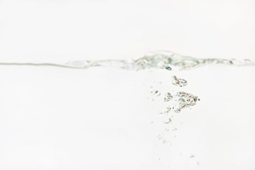 Bubbles in water as its poured into aquarium tank, splashes on surface, white background