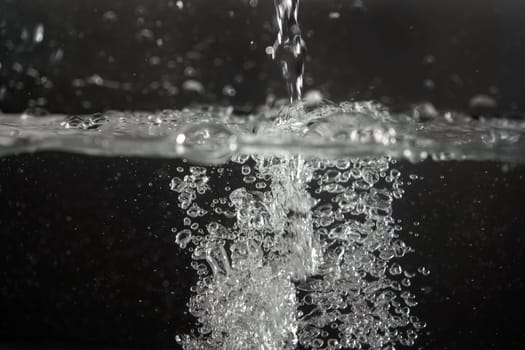 Water splashing as it's poured into aquarium tank, black background