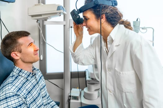 Female ophthalmologist checking the retina of a patient using the light of a retinoscope