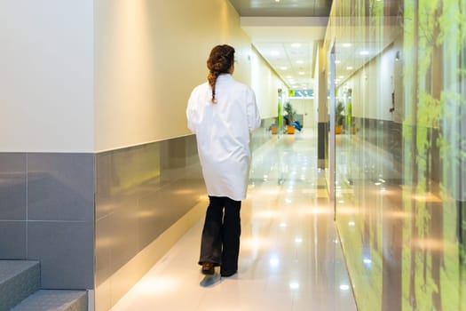 Rear view of a female ophthalmologist walking along a corridor in the clinic