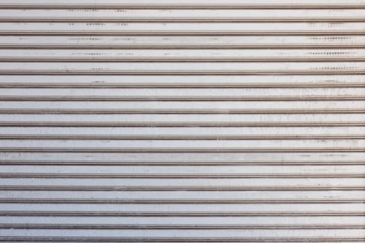Closeup of a weathered and dirty metal shutter with horizontal folding lines