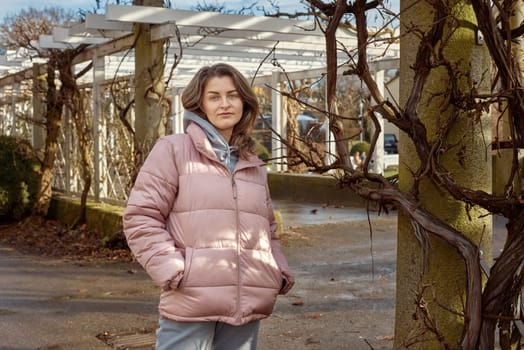 Young beautiful pretty tourist girl in warm hat and coat with backpack walking at cold autumn in Europe city enjoying her travel in Zurich Switzerland. Outdoor portrait of young tourist woman enjoying sightseeing