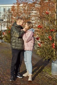 Portrait of young attractive people, lovely couple enjoying cozy atmosphere on fair in Christmas Eve. Spending time together. Concept of national traditions, winter holidays, fashion, festivities