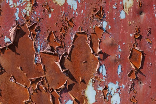 red peeling paint on sheet steel surface under direct sun light - full-frame background and texture