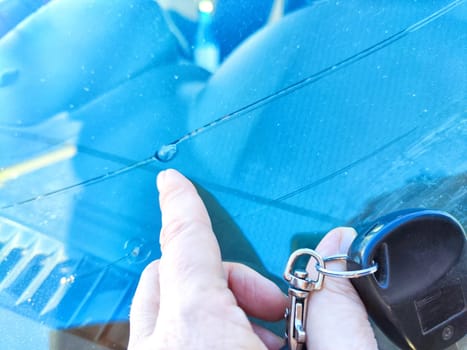 Woman Pointing Out Chip on Her Car's Windshield in Bright Daylight. Finger indicating a small chip on a vehicles windshield