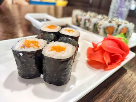 Sushi rolls with fresh ingredients served on platter. Japanese Sushi Rolls on White Plate With Ginger Garnish. Blurred and Partial focus