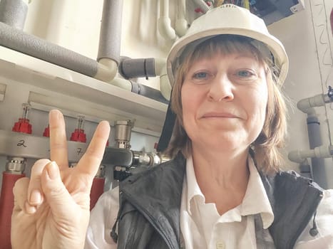 Female middle aged Technician Adjusting Industrial Water Filtration System. Woman services a water filtration unit and posing for photo or selfie