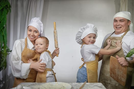 Cute oriental family with mother, father, daughter, son cooking in kitchen on Ramadan, Kurban-Bairam, Eid al-Adha. Funny family at a cook photo shoot. Pancakes, pastries, Maslenitsa, Easter