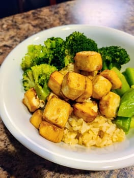 Inviting vegan meal with crispy tofu, fresh broccoli, and flavorful yellow rice, prepared and served in a homey Indiana kitchen.