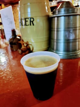 Fresh pint of dark stout on a rustic bar top in a cozy Indiana pub, offering a variety of craft beverages