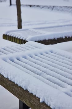 Freshly fallen snow blankets a serene wooden bench in downtown Fort Wayne's Freimann Square, capturing a tranquil winter morning.