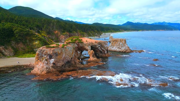 Top view of beautiful coast with rocky arches. Clip. Amazing nature of erosion in sea rocks on coast. Wild beach with coastal cliffs and stone arches.