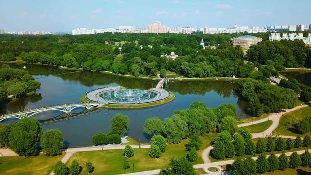 Top view of bridges in city pond with fountains. Creative. Island with bridges and fountains in city pond. Beautiful fountain complex on river island with pedestrian bridges.