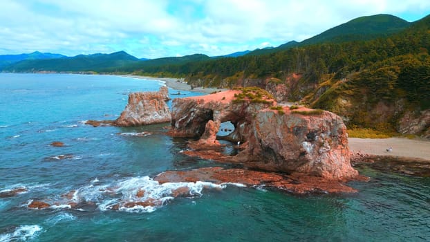 Top view of beautiful coast with rocky arches. Clip. Amazing nature of erosion in sea rocks on coast. Wild beach with coastal cliffs and stone arches.
