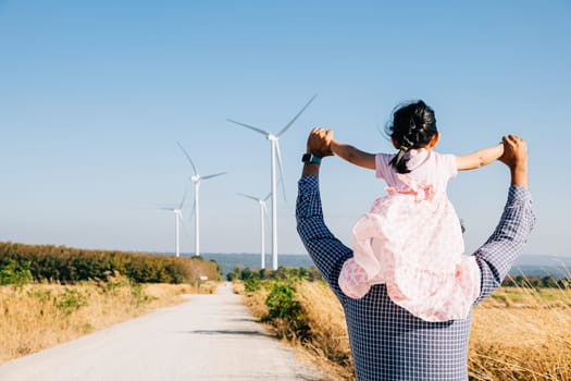 Father joyfully carries daughter at wind farm. Family bonding near turbines symbolizes innovation in renewable energy. A joyful father-daughter moment in the windmill industry. father day concept
