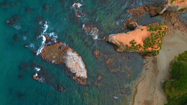Top view of beautiful wild coast with rocks in water. Clip. Coastline with rocks and waves near shore. Inspiring nature of sea coast with variety of rocks.