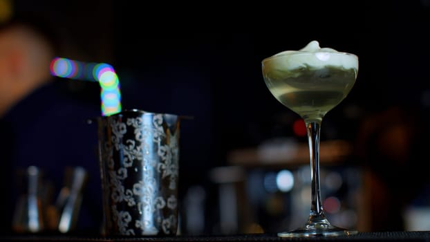 A professional bartender preparing an alcoholic cocktail with cream topping. Media. Making a beverage at the bar or disco club
