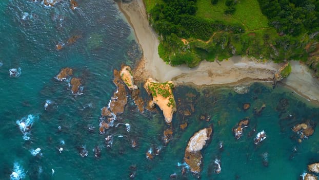 Top view of beautiful wild coast with rocks in water. Clip. Coastline with rocks and waves near shore. Inspiring nature of sea coast with variety of rocks.