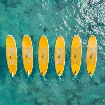 A set of yellow surfboards on a blue sea background.