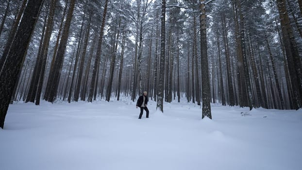 Man walks and dances in winter forest. Media. Stylish man walks in winter forest. Drunk or cheerful man dancing on walk in winter forest.